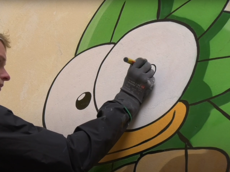 Mikkel Jessen tegner en fugl på en mur