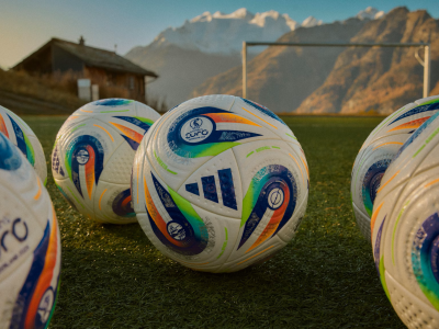 Closeup af fodbolde på fodboldbane med bjerglandskab i baggrunden