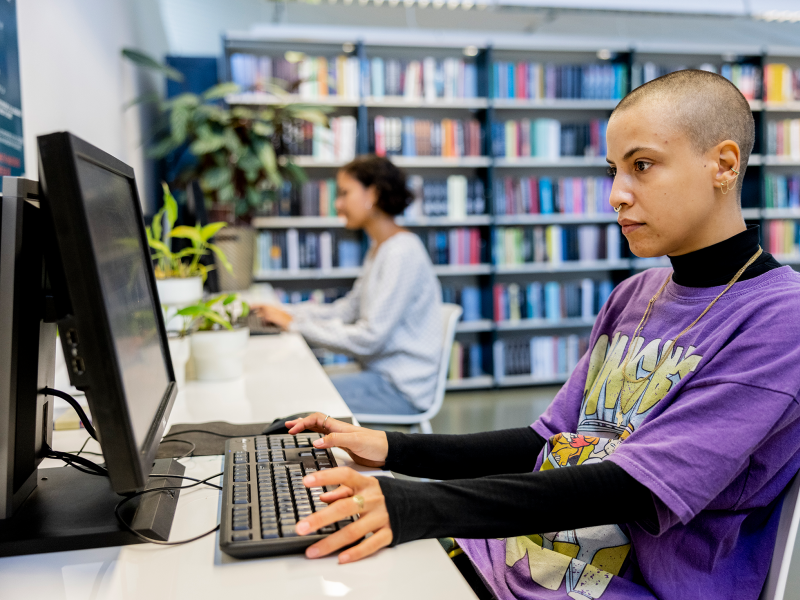 To kvinder ved offentlige pc'er på et bibliotek