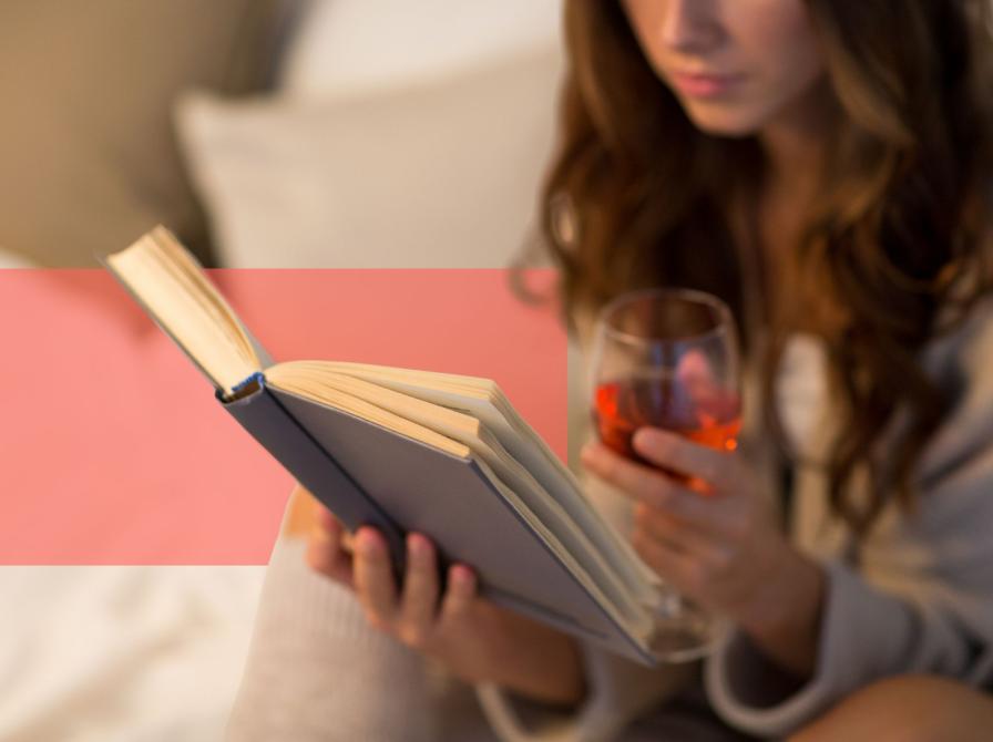 Kvinde læser en bog med et glas rødvin